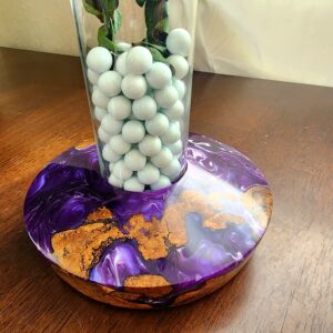 Handcrafted red oak burl and purple epoxy vase base holding glass cylinder with eucalyptus stems on wooden table in natural light